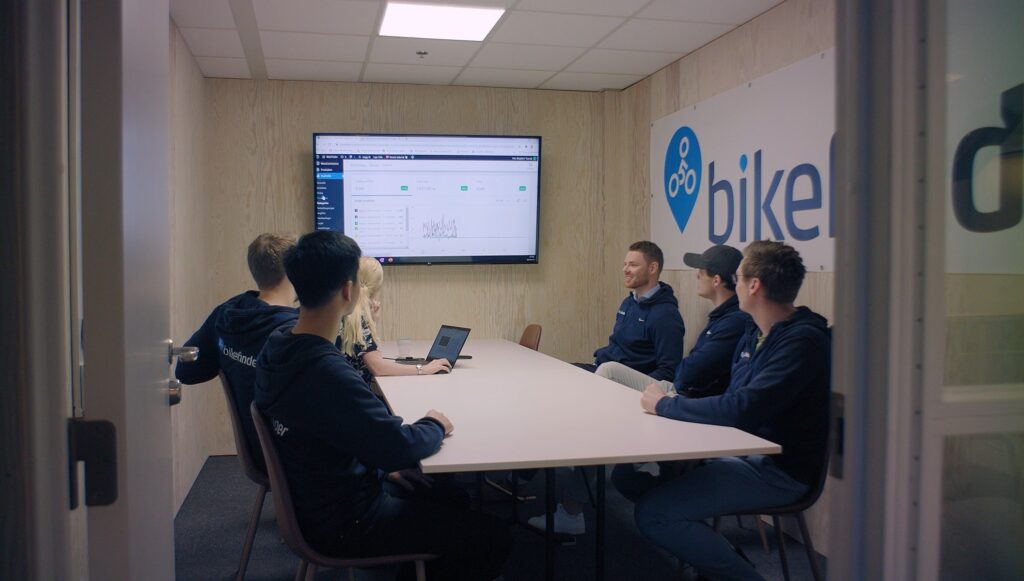Employees sitting in a meeting room around a table looking at a screen