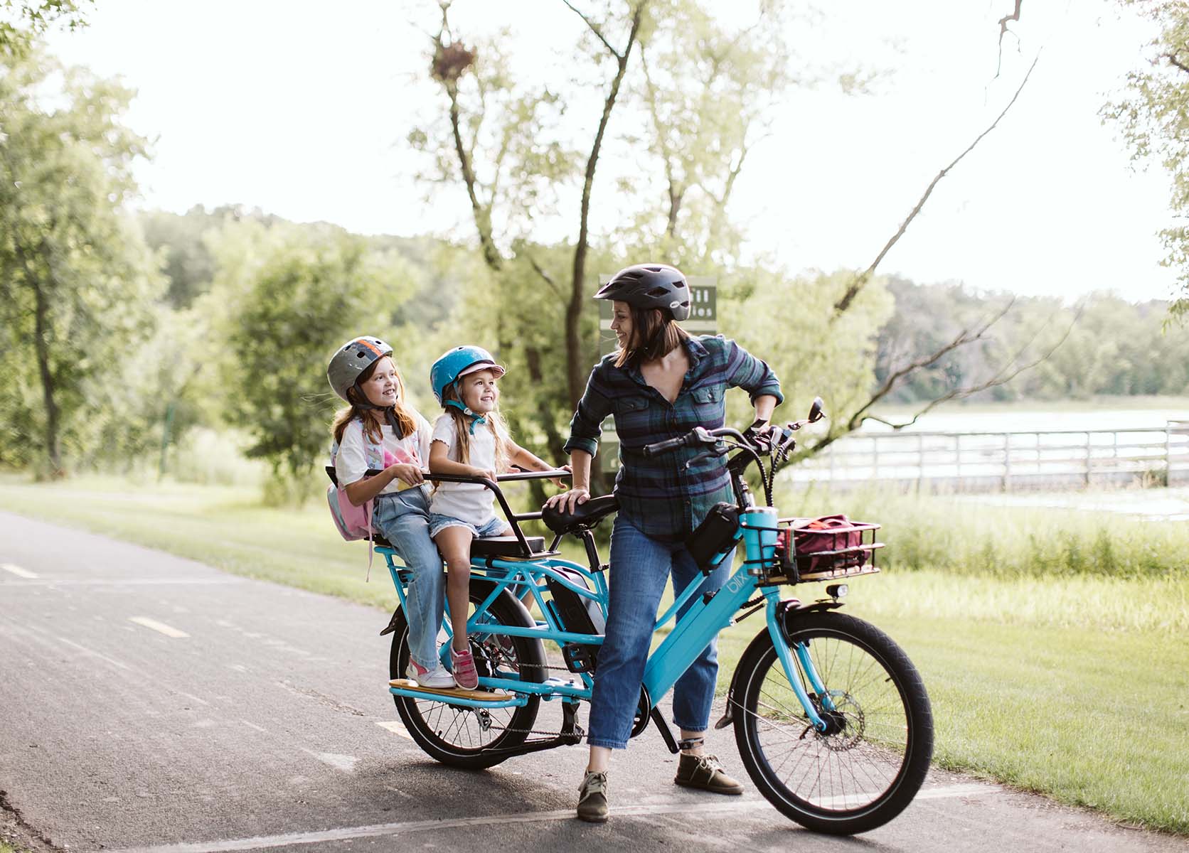 A Minneapolis mom rides her bright blue Blix long tail cargo bike with two kids on the back, heading to school, protected by a hidden BikeFinder tracker